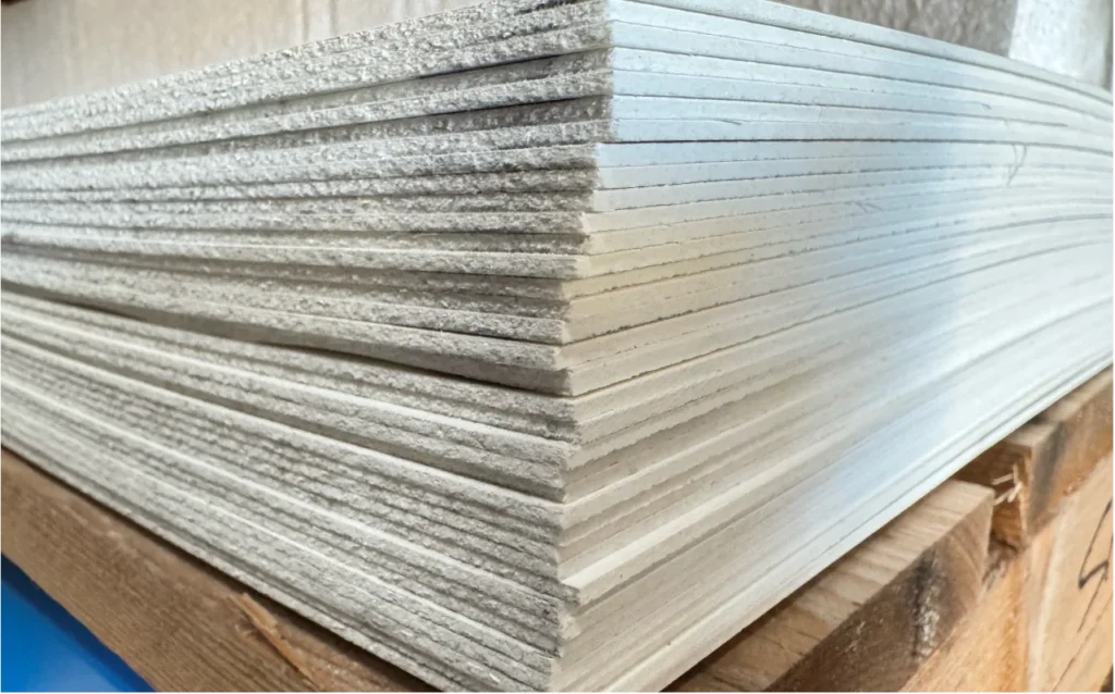 Une pile de plaques fibrées lisses conforme HACCP en stock chez ISOSELL prêt à être envoyée pour une commande sur le site en ligne.