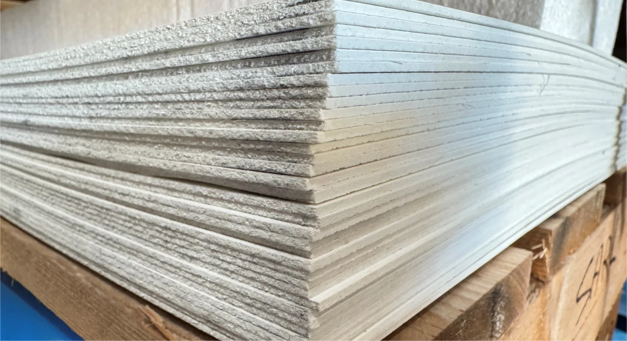 Pile de plaques fibrées lisses en stock chez ISOSELL pour faire des revêtements murs et plafonds lisse conformes aux normes HACCP