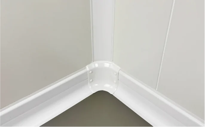 Angle intérieur monté sur plinthes PVC avec cache-vis clipsé, environnement agroalimentaire dans une chambre froide
