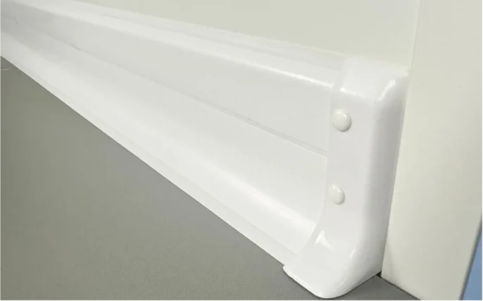 Embout hygiénique en PVC blanc fixé par rivets à l’extrémité d’une plinthe à lèvres souples distribuées par ISOSELL, assurant une finition mur-sol propre, étanche et conforme aux normes HACCP dans un environnement professionnel.